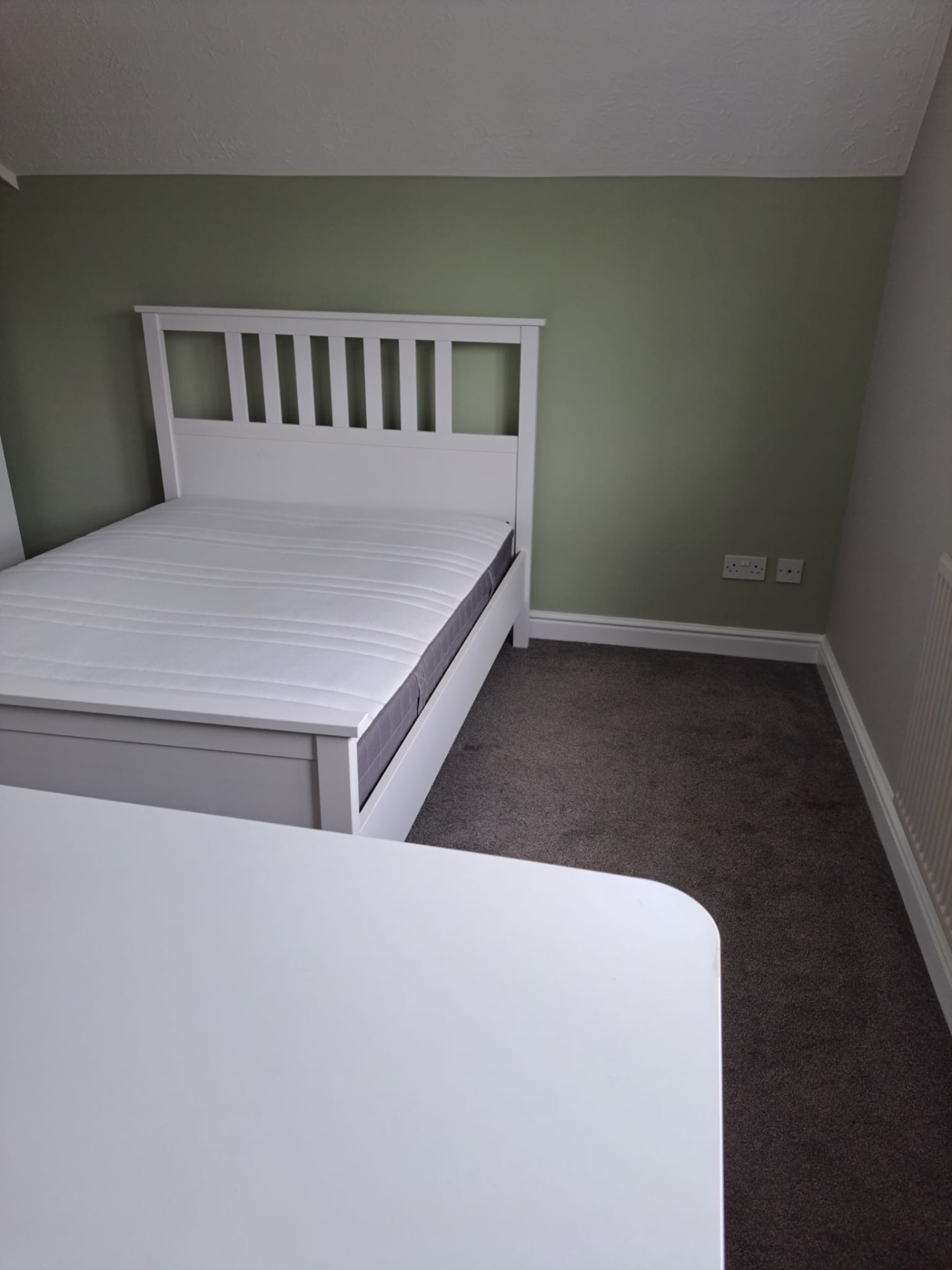 Bedroom redecorated with a soft green feature wall and fresh white woodwork